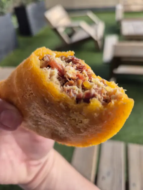 Empanada mordida que deja ver el relleno de carne y papa