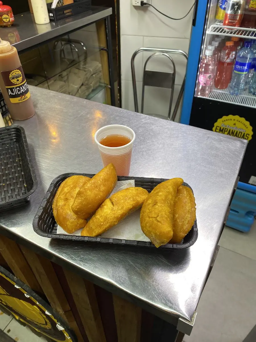 Empanadas y pastel en bandeja con un vasito de salsa