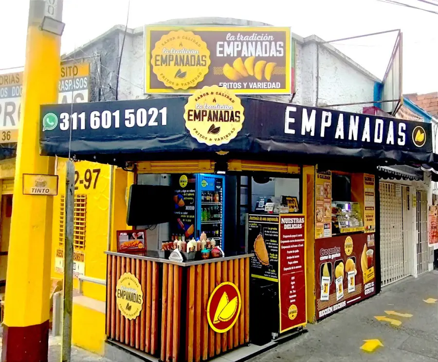 Local de Empanadas la Tradición: esquina amarilla con aviso, vitrina y número de WhatsApp