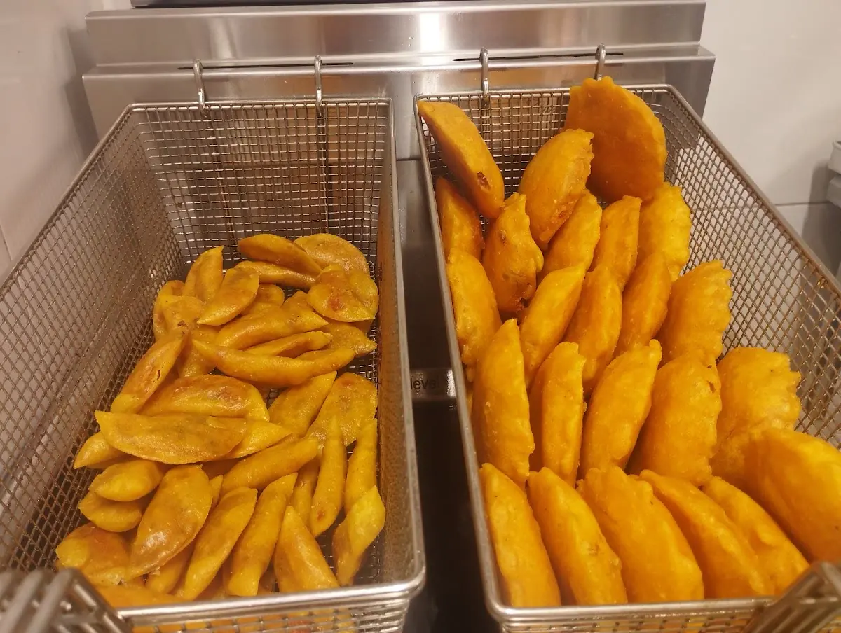 Dos canastas de freidora llenas de empanadas y empanaditas doradas, recién hechas